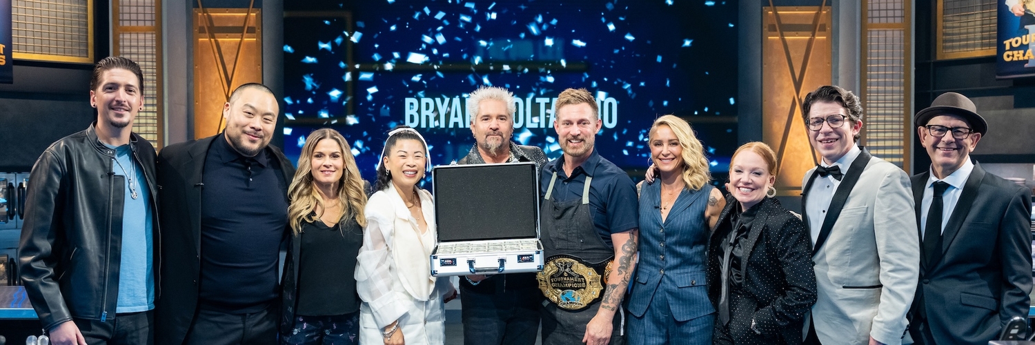 Guy Fieri and winner Bryan Voltaggio with Floor Commentators Tiffani Faison and Justin Warner, judges Cat Cora, Mei Lin, Brooke Williamson, and David Chang, and reporters Hunter Fieri and Simon Majumdar, as seen on TOC VII