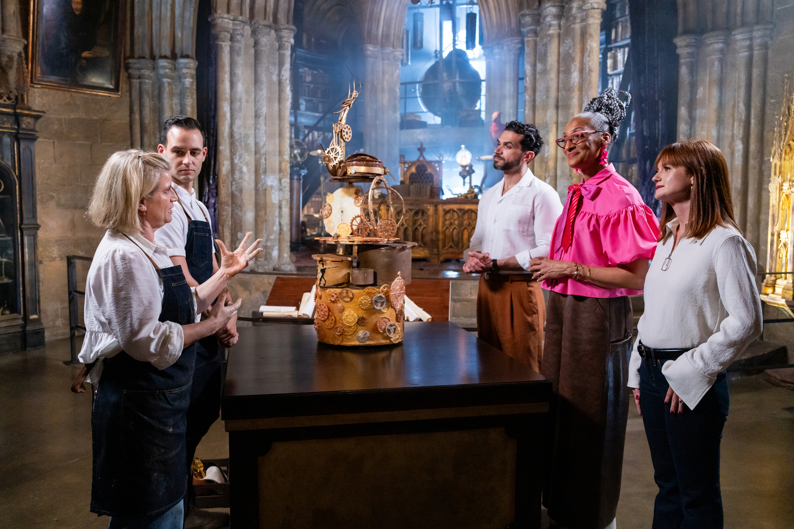 Judges Carla Hall, Jozef Youssef and special guest Bonnie Wright evaluate a competitors showpiece in Dumbledore's Office Food Network Harry Potter Wizards of Baking