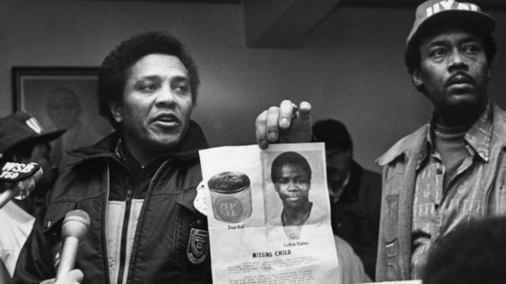 Eldrin Bell showing photo of Lubie Geter at press conference (1981) 