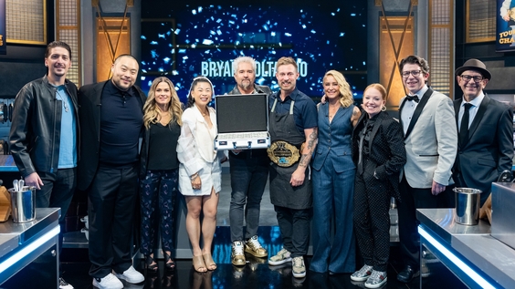 Guy Fieri and winner Bryan Voltaggio with Floor Commentators Tiffani Faison and Justin Warner, judges Cat Cora, Mei Lin, Brooke Williamson, and David Chang, and reporters Hunter Fieri and Simon Majumdar, as seen on TOC VII